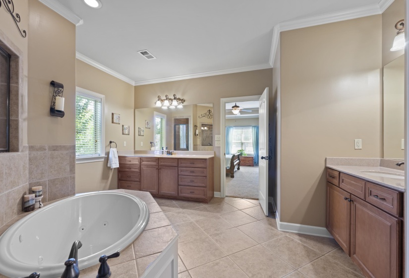 Relaxing primary bath with a whirlpool tub, tiled walk-thru shower, dual vanities, and spacious layout designed for comfort.