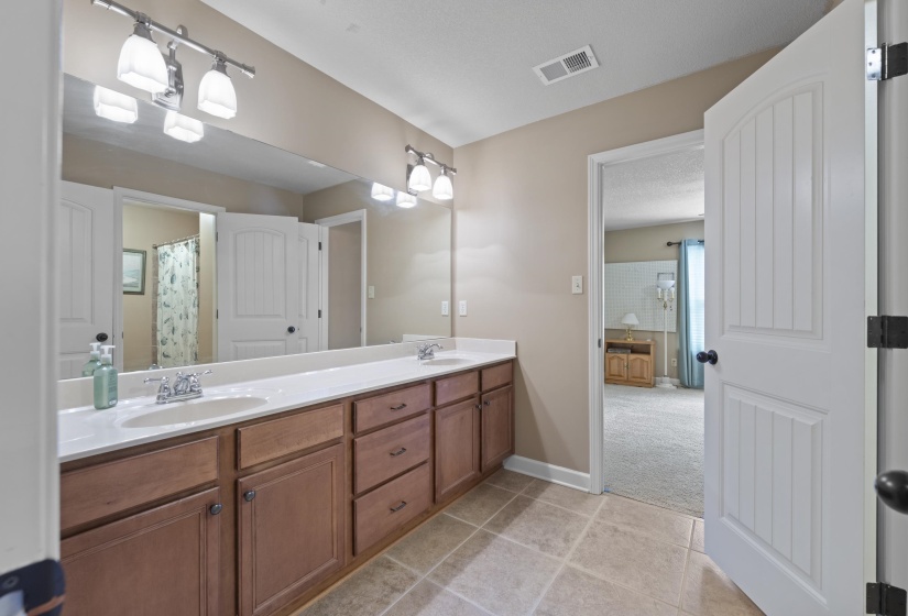 Spacious bathroom with an extended double vanity, abundant cabinet storage, tile flooring, and plenty of counter space for busy mornings.