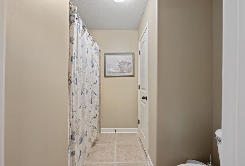 Functional full bathroom featuring tile flooring, tub/shower combination, linen storage, and a clean neutral design.