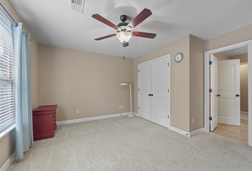 Well-sized secondary bedroom with double-door closet, ceiling fan, and direct access to the adjoining bathroom for added convenience and comfort.
