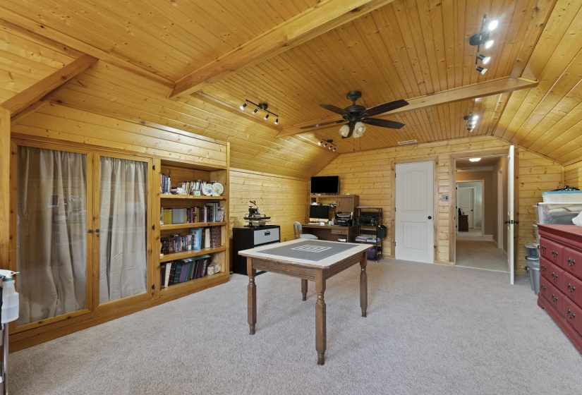 Warm and inviting bonus room with custom built-ins, vaulted wood ceiling, and endless possibilities for entertaining, working, or relaxing.
