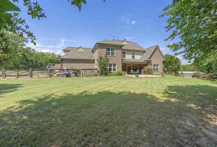 Large, level backyard with lush green space, mature trees, and scenic surroundings offering both privacy and room to play or entertain.