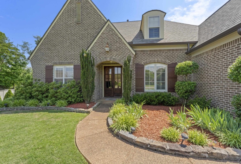 Beautiful curb appeal with manicured landscaping, charming brick exterior, and elegant double front doors creating a warm and inviting first impression.