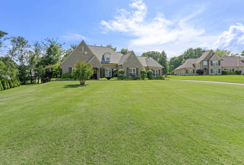 Impressive front exterior featuring elegant architectural details, lush landscaping, and an expansive yard that creates a private estate feel.
