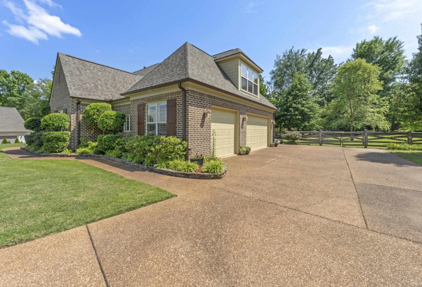 Spacious side-entry garage with an oversized driveway offering ample parking, beautiful landscaping, and easy access to the backyard and home.