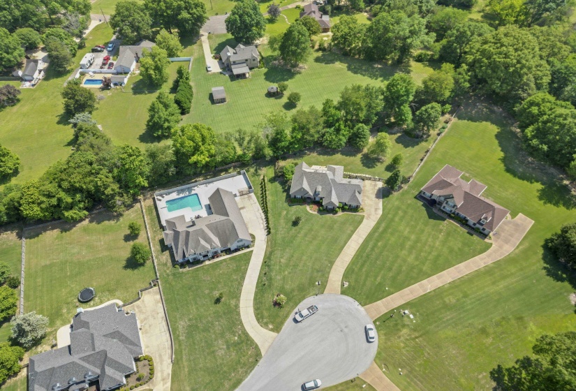 Beautiful aerial view showcasing the quiet cove location, spacious .81-acre lot, and surrounding mature trees that create a private and peaceful setting.