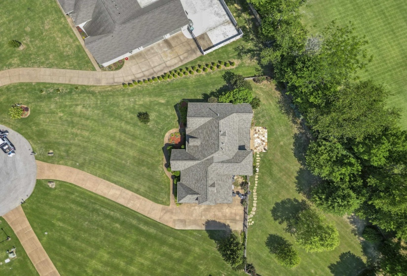 Overhead aerial view highlighting the huge backyard, extended driveway, landscaping, and serene wooded backdrop.