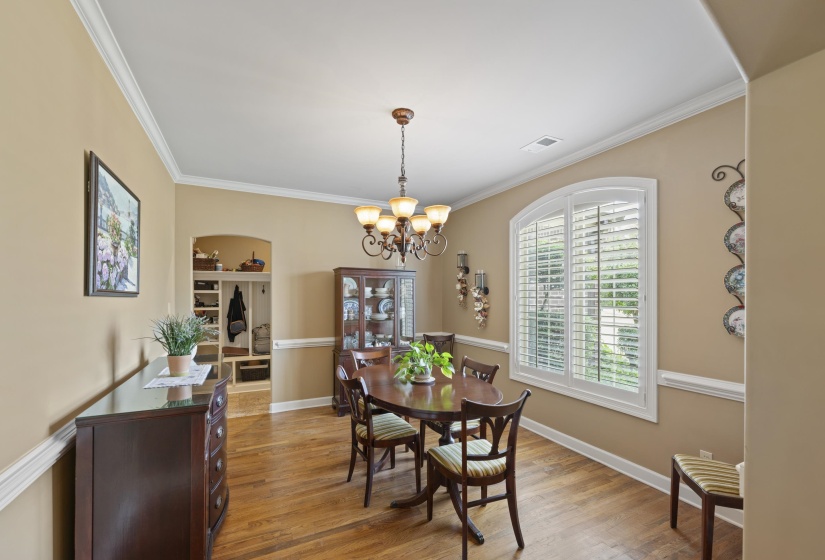 Lovely dining room with hardwood floors, chair rail molding, plantation shutters, and a dazzling chandelier perfect for gatherings.