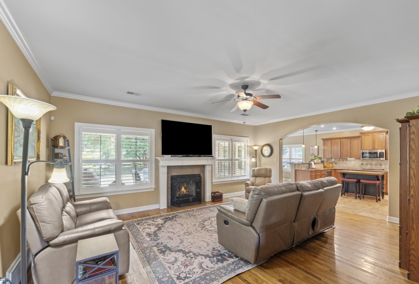 Spacious great room with beautiful hardwood floors, plantation shutters, cozy gas log fireplace, and open flow into the kitchen.