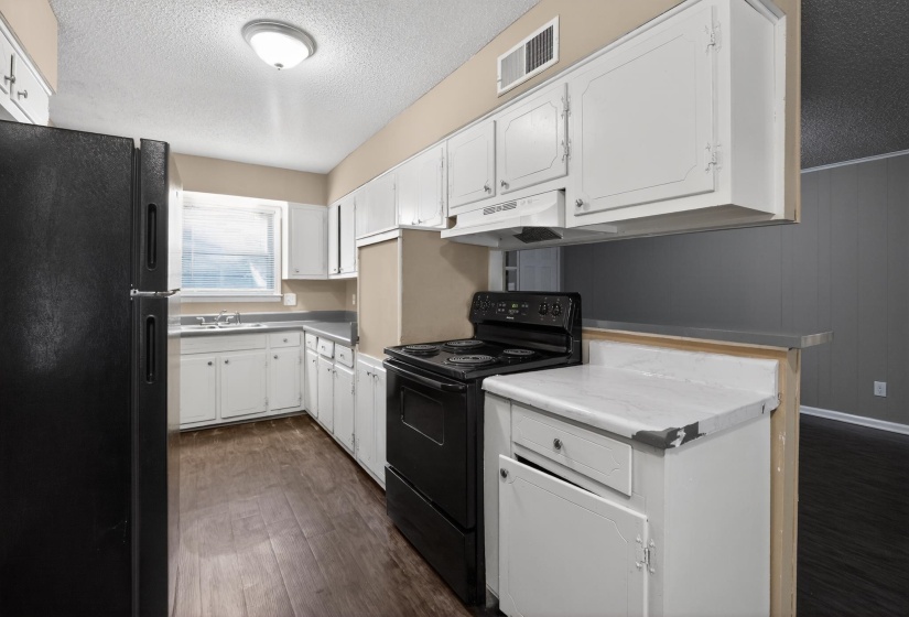 Kitchen featuring white cabinetry, wood-finish flooring, and black appliances