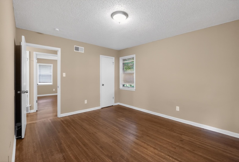 Spacious room featuring wood-finish flooring, neutral-toned walls, and white trim