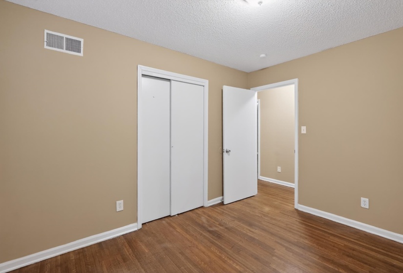 Room with wood-finish flooring, tan painted walls, white trim, and a white ceiling