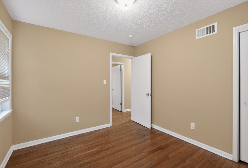 Room featuring wood-finish flooring, neutral wall paint, and white trim