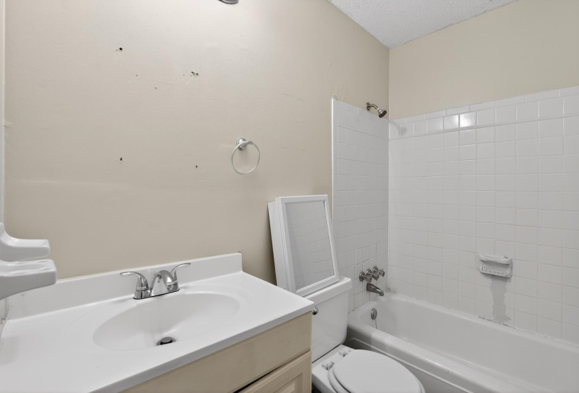 Bathroom featuring a single vanity with an integrated sink, a chrome faucet, and a white tiled shower/tub combination