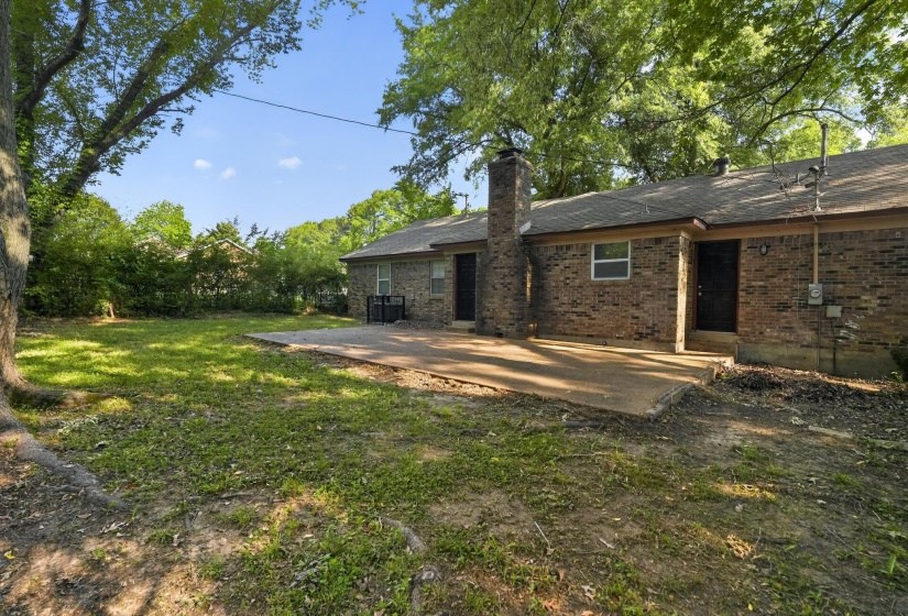 Expansive rear yard featuring mature trees and a concrete patio