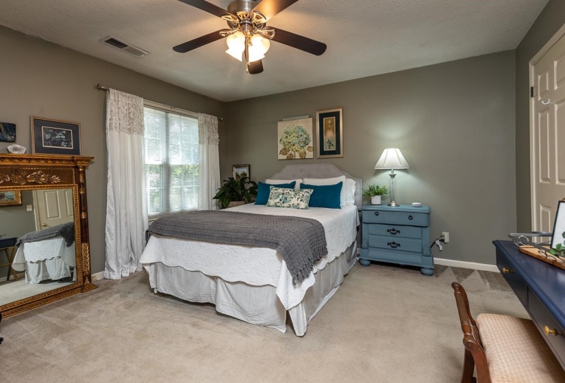 Carpeted bedroom featuring a textured ceiling and ceiling fan