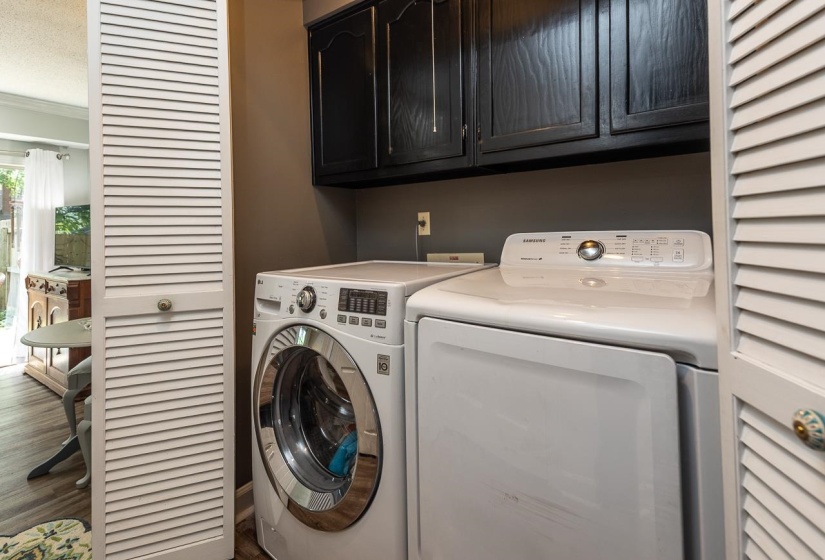 Laundry area featuring separate washer and dryer, cabinet space, and wood finished floors