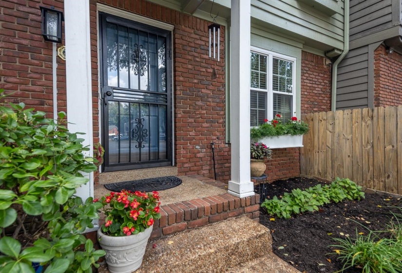Property entrance featuring covered porch and brick siding