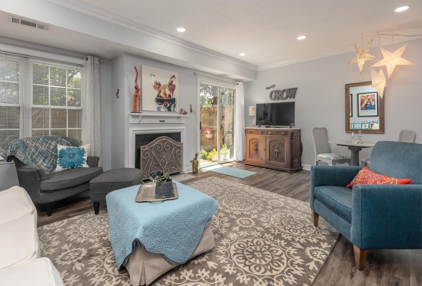Living area featuring wood finished floors, crown molding, a fireplace with flush hearth, and recessed lighting