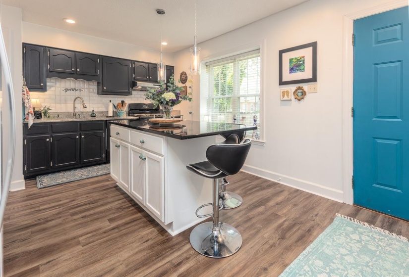 Kitchen with a breakfast bar area, decorative backsplash, dark wood finished floors, dark countertops, and stove