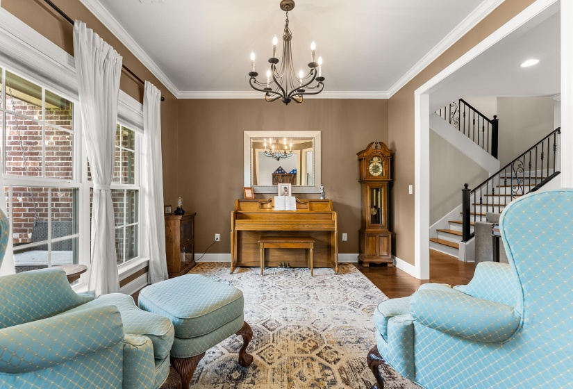 Formal living area featuring crown molding, a decorative chandelier, and extensive natural light from multiple windows