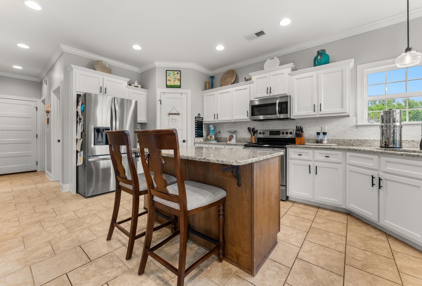 Kitchen featuring white cabinetry, stainless steel appliances, speckled stone countertops, and a tile backsplash