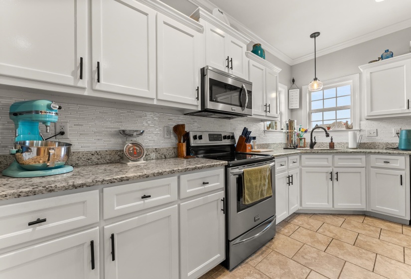 Kitchen featuring white shaker-style cabinetry, stainless steel appliances, granite countertops, and a white mosaic tile backsplash