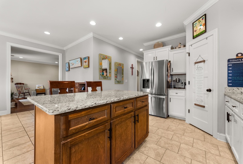 Kitchen featuring a wooden island with a light granite countertop, tile flooring, white cabinetry, recessed lighting, and stainless steel appliances