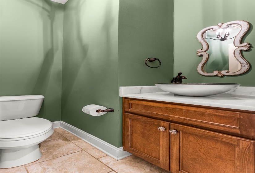 Bathroom vanity featuring a vessel sink, stone countertop, wood-finish cabinetry, and decorative mirror