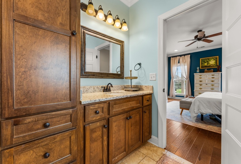 Wood cabinetry with integrated storage and a granite countertop vanity featuring an undermount sink