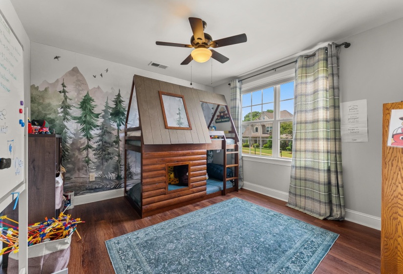 Room featuring wood-finish flooring, a ceiling fan, and a large window with white trim