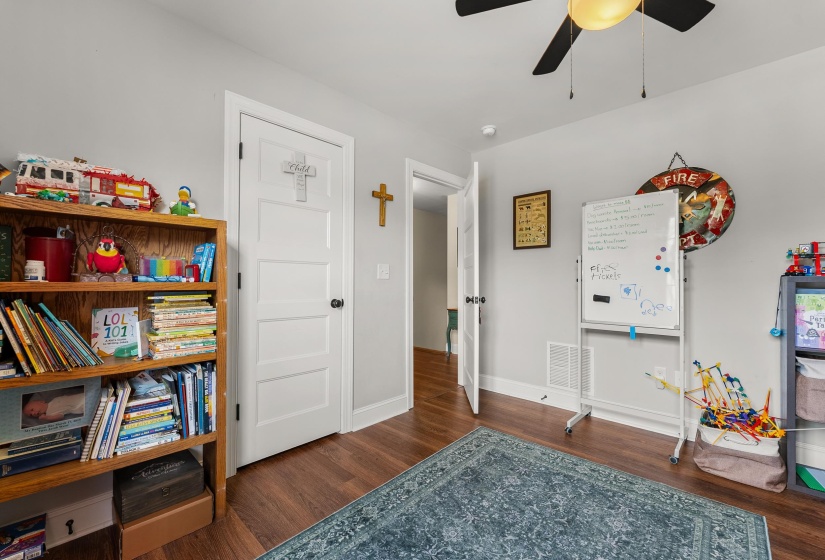 Room featuring wood-finish flooring, a ceiling fan with integrated lighting, and light gray wall paint