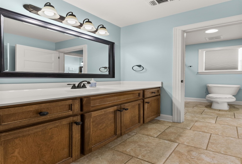 Bathroom featuring a vanity with wood cabinetry, a white countertop, and a rectangular undermount sink