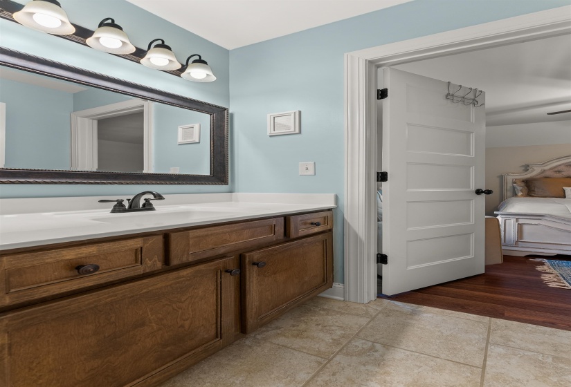 Bathroom featuring a single vanity with a white countertop, dark wood-finish cabinetry, and a framed mirror