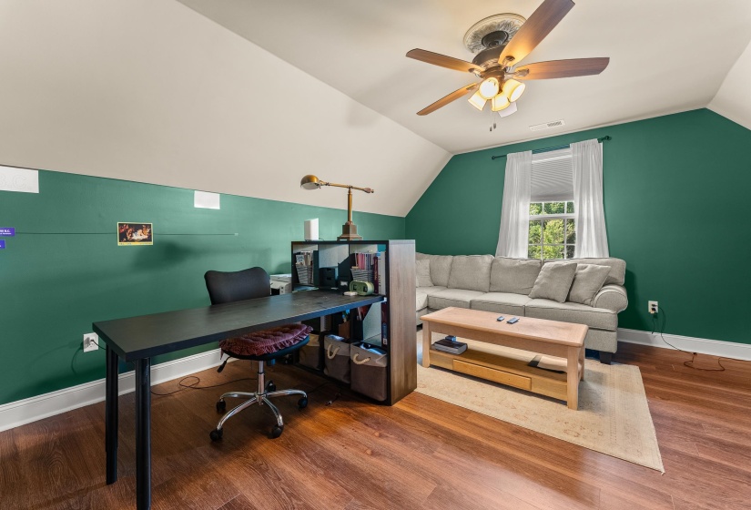 Spacious room featuring wood-finish flooring, a contemporary ceiling fan, and angled white ceilings