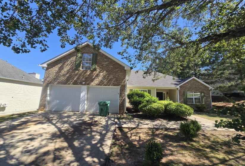 Brick and siding exterior featuring a two-car garage, pitched roofline, and established front landscaping