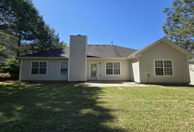 Expansive backyard featuring a concrete patio and a well-maintained lawn