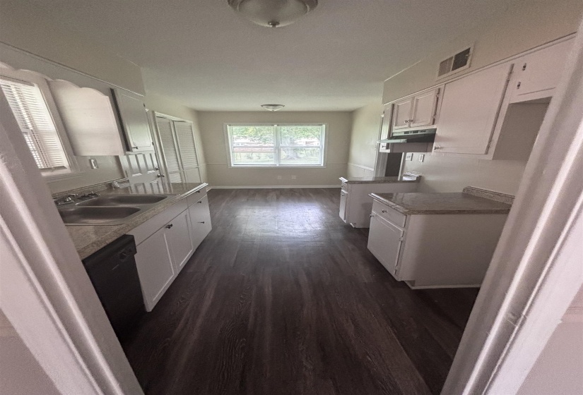 Galley kitchen featuring wood-finish flooring, white cabinetry, and light-toned countertops