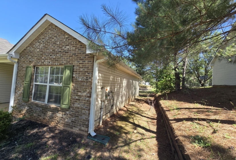 Brick exterior with a gabled roofline, featuring a double-hung window with green shutters