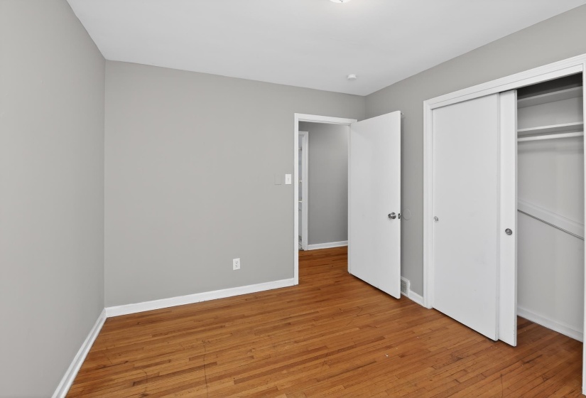 Bedroom featuring wood-finish flooring, light gray wall paint, and white trim