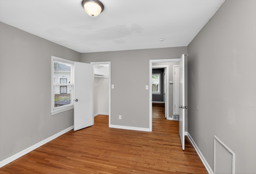 Room featuring wood-finish flooring, light grey walls, white trim, and a ceiling-mounted light fixture