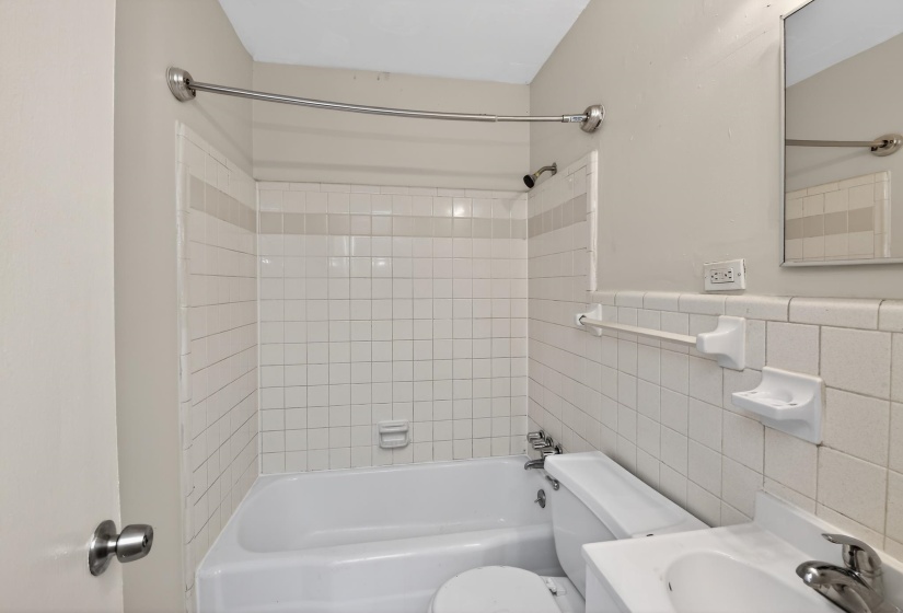 Bathroom featuring a white subway tile surround, white tub, and white toilet