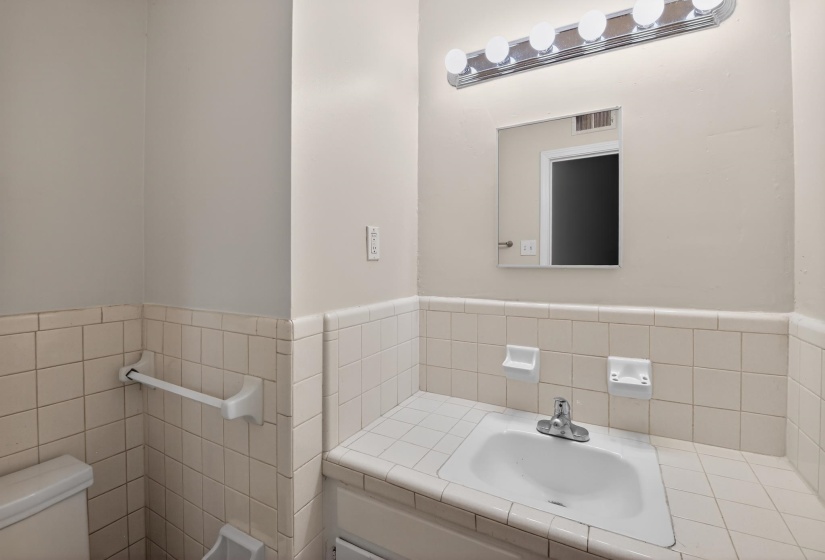Bathroom featuring a vanity with an integrated sink, a chrome faucet, and a wall-mounted mirror