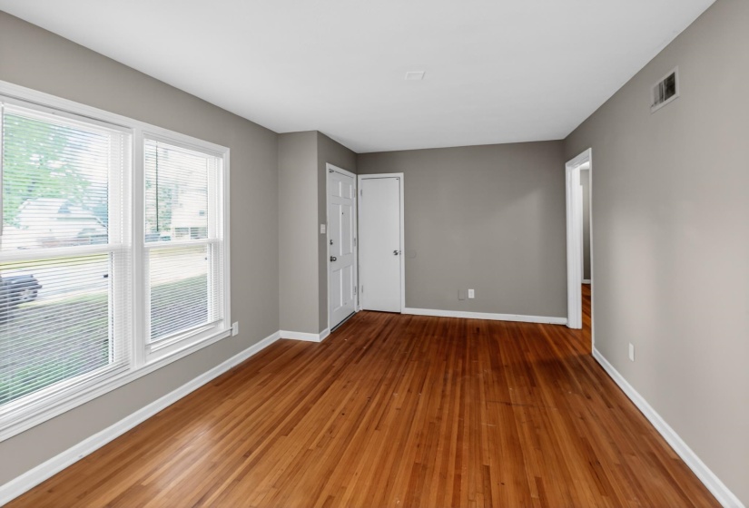 Spacious room with wood-finish flooring, light gray wall paint, and white trim