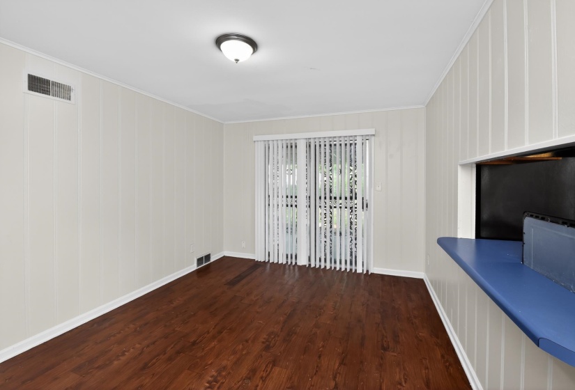 Spacious room featuring wood-finish flooring, vertical paneling, and a pass-through window with a blue countertop