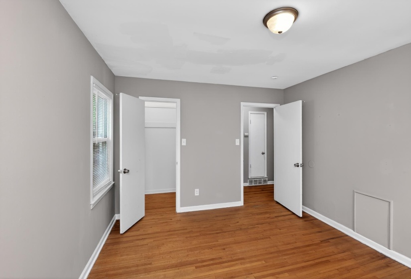 Hardwood flooring featured in a room with neutral gray walls, white trim, and a window with blinds