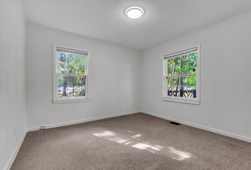 Neutral wall paint, plush carpeting, two sash windows, baseboard trim, and a ceiling-mounted light fixture