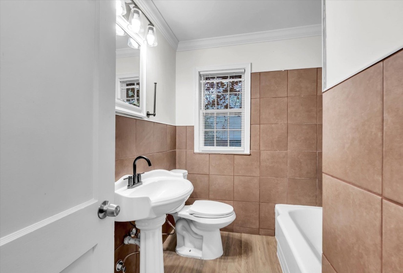 Pedestal sink with black-finish faucet, subway-tiled walls, and a window with blinds