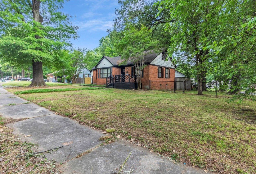 Brick exterior with a peaked roofline, front porch, and mature trees on the property