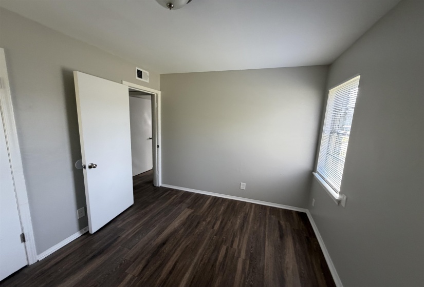Interior room featuring wood-finish flooring, light gray wall paint, and white baseboards